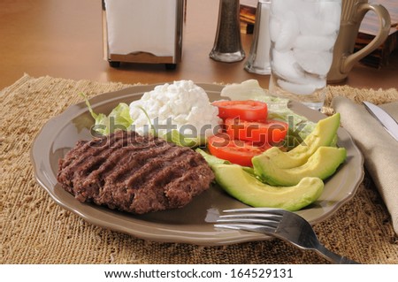 A grilled hamburger patty with avocado, tomato and cottage cheese