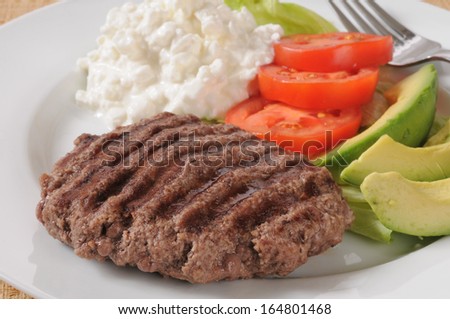 Closeup of a grilled sirloin patty with avocado and cottage cheese