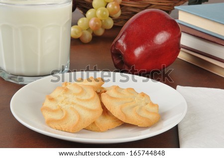 Cookies and milk with an apple next to schoolbooks