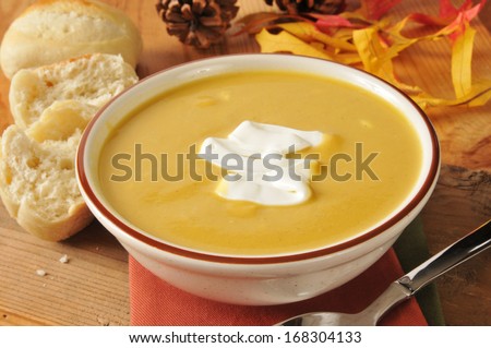 A bowl of butternut squash soup with a dollop of sour cream