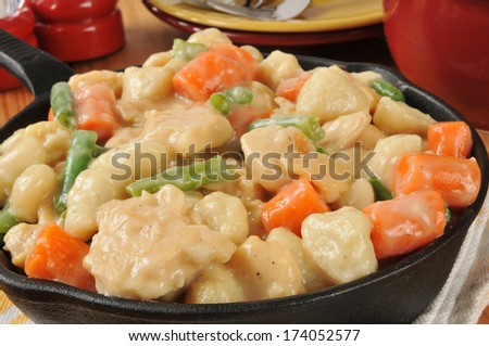 Closeup of a cast iron skillet of chicken and dumplings with carrots and green beans