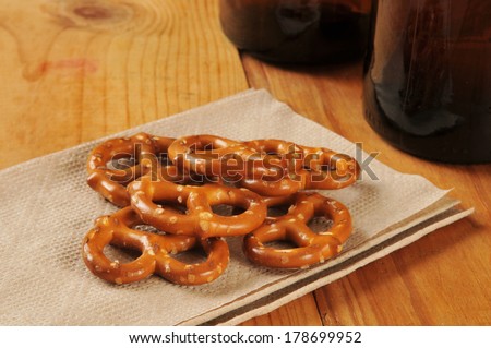 Salted pretzels on a bar napkin with bottles of beer