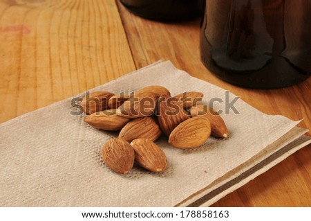 Almonds on a bar napkin with bottles of beer in the background