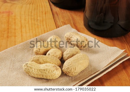 Peanuts in the shell on a bar napkin with bottles of beer in the background