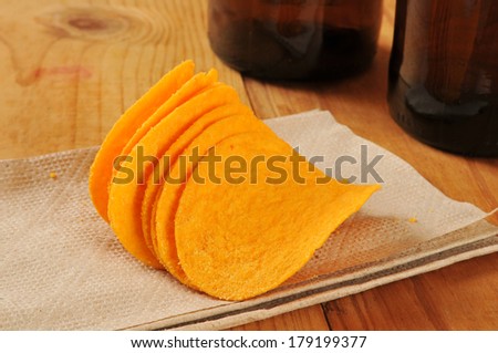 Cheese flavored potato crisps on a bar napkin with bottles of beer