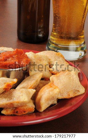Pizza roll snacks with marinara sauce and beer