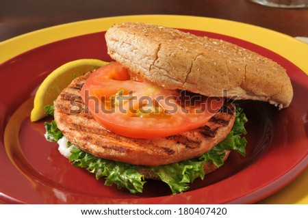 Closeup of a grilled salmon burger with tomato and lettuce