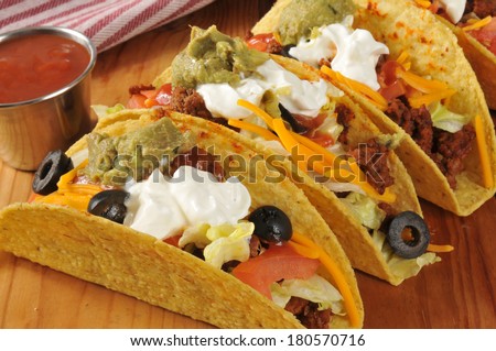 Beef tacos with lettuce, tomato, black olive, cheddar cheese, guacamole and sour cream