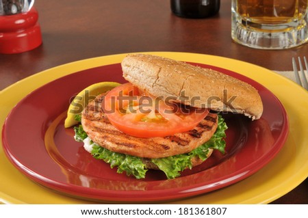 Closeup of a grilled salmon burger with a mug of beer