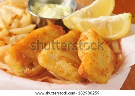 Battered fish sticks with french fries, lemon wedges and tarter sauce closeup