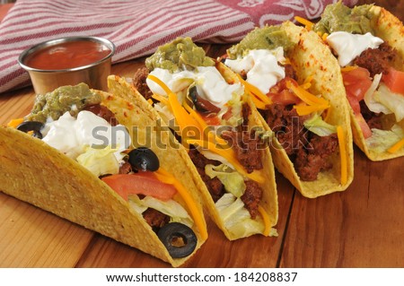 Beef tacos with sour cream, guacamole and cheddar cheese