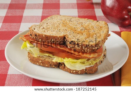 A BLT sandwich on sprouted whole grain nut and seed bread with an apple