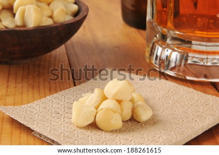 Macadamia nuts on a napkin on a bar counter with a mug of beer