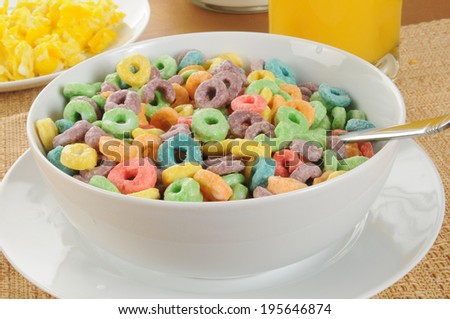 A bowl of fruit flavored oat ring cereal with scrambled eggs