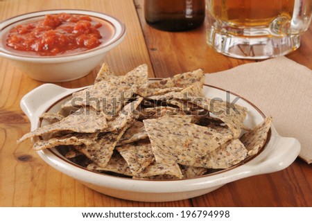 A bowl of rice and bean tortilla chips with salsa and beer