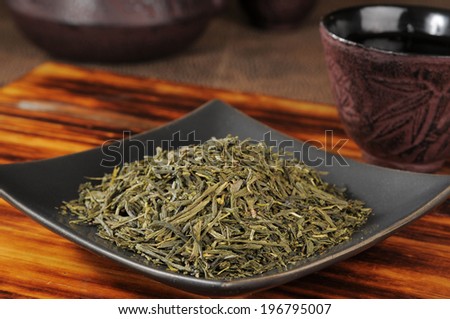 A sample dish of whole leaf green tea with a teapot