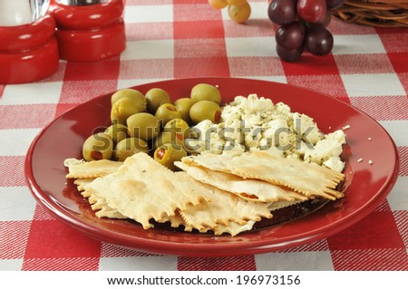Snack plate of flatbread crackers with feta cheese and stuffed green olives
