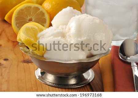 A silver serving dish of lemon sorbet on a wooden table