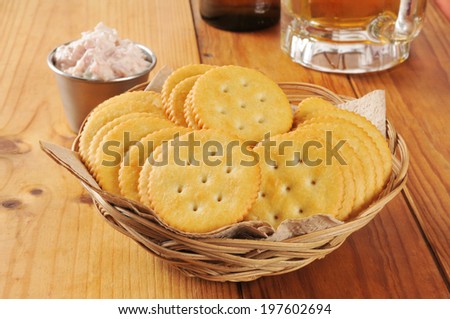 a basket of crackers with deviled ham and a mug of beer