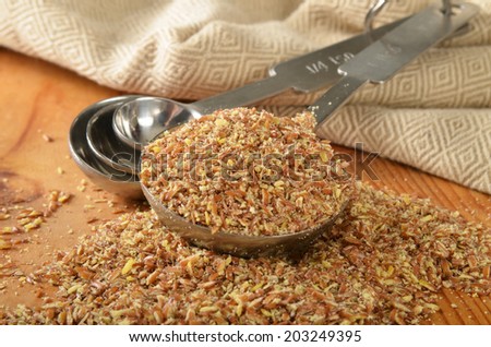 Course ground organic flax seed in a measuring spoon, shallow depth of field, focus on spoon.
