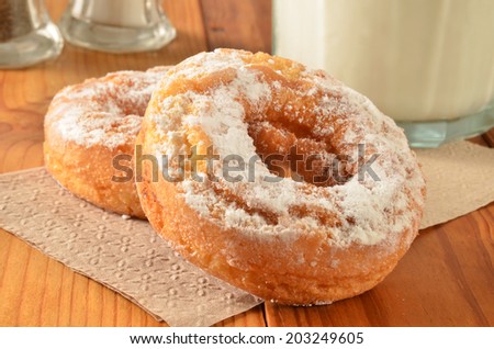 Cake donuts with powdered sugar and milk on a rustic wooden table
