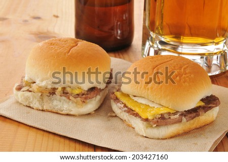 Mini cheese burger sliders with diced onions and beer on a rustic wooden bar counter