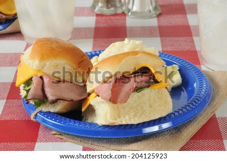 Roast beef sliders on a picnic table with potato salad