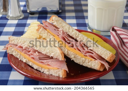 A ham and cheese sandwich on a picnic table with potato chips