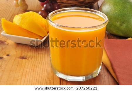 A glass of fresh mango juice with a bowl of sliced mango