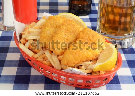 Fish and french fries wrapped in newspaper in a basket with beer