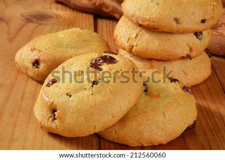 A stack of fresh baked cranberry orange cookies on a rustic wooden counter