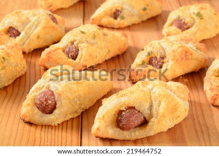 Mini beef hot dogs wrapped in buttery pastry and topped with parmesan cheese