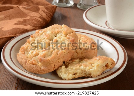 A plate of gourmet macadamia nut cookies with a cup of coffee