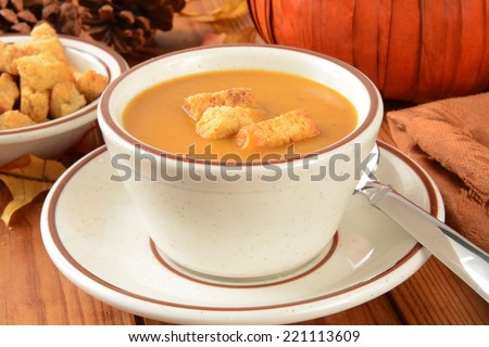 A cup of pumpkin soup with cornbread croutons on a holiday table