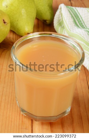 A glass of fresh organic pear juice on a rustic wooden table