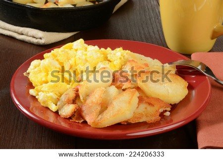 Home fried potatoes and scrambled eggs with a cast iron serving skillet in the background