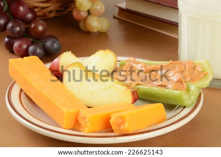 A plate of cheese, celery with peanut butter and apples after school