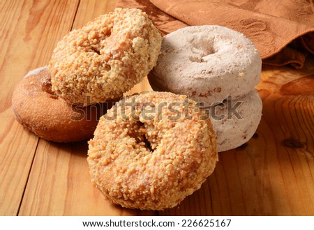 A stack of assorted cake donuts on a rustic wooden table