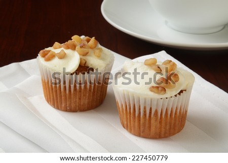 Carrot cake cupcakes with nuts on top and a cup of coffee