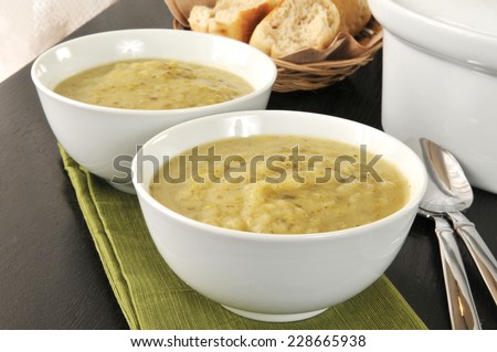 Bowls of potato leek soup with dinner rolls