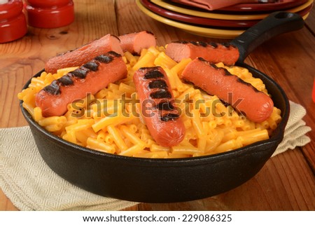 macaroni and cheese with grilled hot dogs in a cast iron skillet