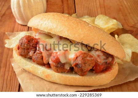 A meatball sandwich with potato chips on a brown wrapper