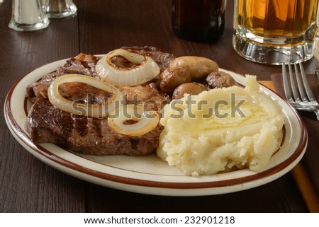 A grilled steak with mashed potatoes and a mug of beer