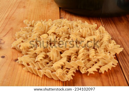 A mound of gluten free Fusilli pasta, made from brown rice and quinoa, with a cooking pot in the background
