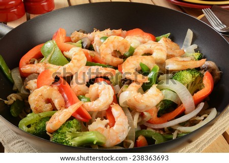 Closeup of shrimp stir fry in a wok with serving plates