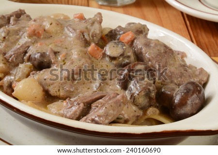 Closeup of a bowl of beef stroganoff in wine sauce with onions and mushrooms