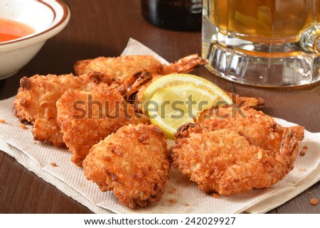 Bar snack, coconut shrimp on a napkin with lemon wedges and a mug of beer