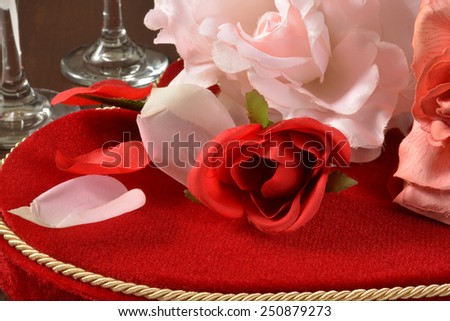 Roses on top of a heart shaped velvet box of chocolates