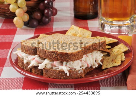 A crab salad sandwich on whole wheat bread with beer in the background