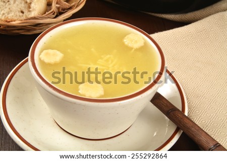 A cup of chicken noodle soup on a dark table